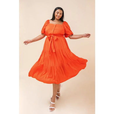 Our India dress is a dress you will want to wear for so many special occasions.  This amazing woven midi dress features a square neckline, with non-functional button -down detail, a self-sash tie, elasticized waist and sleeves at shoulders and arm and tiered skirt.  A rich coral color makes this dress even more stunning.