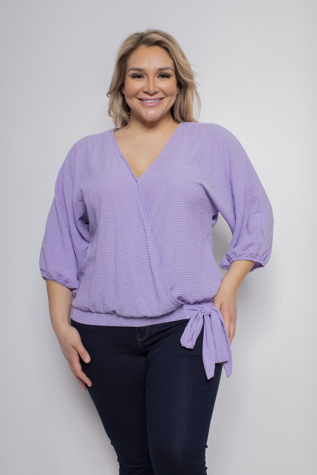 A lovely lavender color top, our Leeann faux wrap side tie blouse is a perfect top for every season.  With the lightweight linen feel, you will be sure to remain cool and comfortable during those hot, humid days while looking stylish.  The details are in the design and this top does not disappoint with its faux wrap front and side tie, stretch banded bottom and 3/4 sleeves.  A keyhole button closure is found in the back at the neckline.  Color- Lavender. 3/4 sleeves.