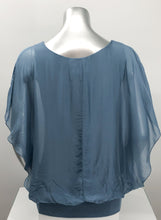 Load image into Gallery viewer, A free-flowing fabrication creates a stunning top in a slate blue color. Top is lined with a knit covered by a gorgeous silk. Bottom is banded in the same color. Create a classy and fashion forward look with our Darla by pairing it with our M Made in Italy silk bottoms.    Color- Slate blue. Knit lining slate blue. Flowy fabrication on the outside. A knit lining on the inside prevents see through.  Banded bottom.
