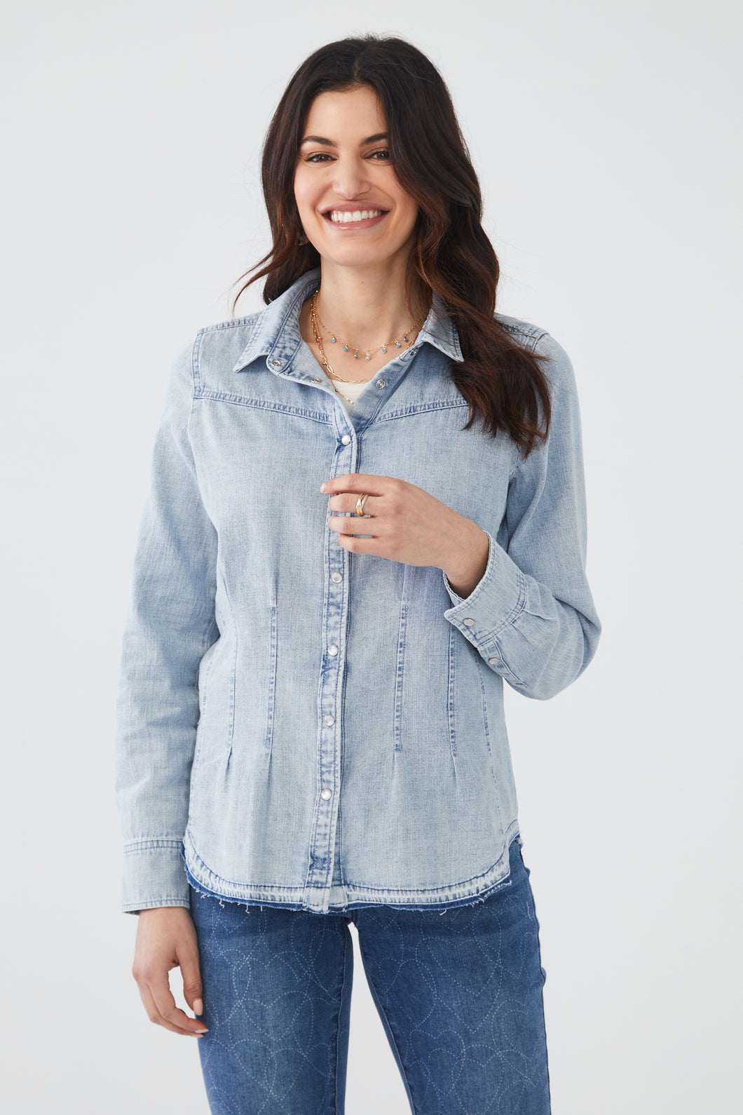 The pleating on this light blue wash top gives our Wen a classic feminine touch, while the pearlized buttons add an extra touch. Slight fray on the bottom hem adds a bit of edge to this fabulous top. This is a style you want to add to your closet as it can be worn alone or layered over your favorite top.  Color- Light blue wash. Pearlized buttons.  Button down. Button cuff. Waist pleating.