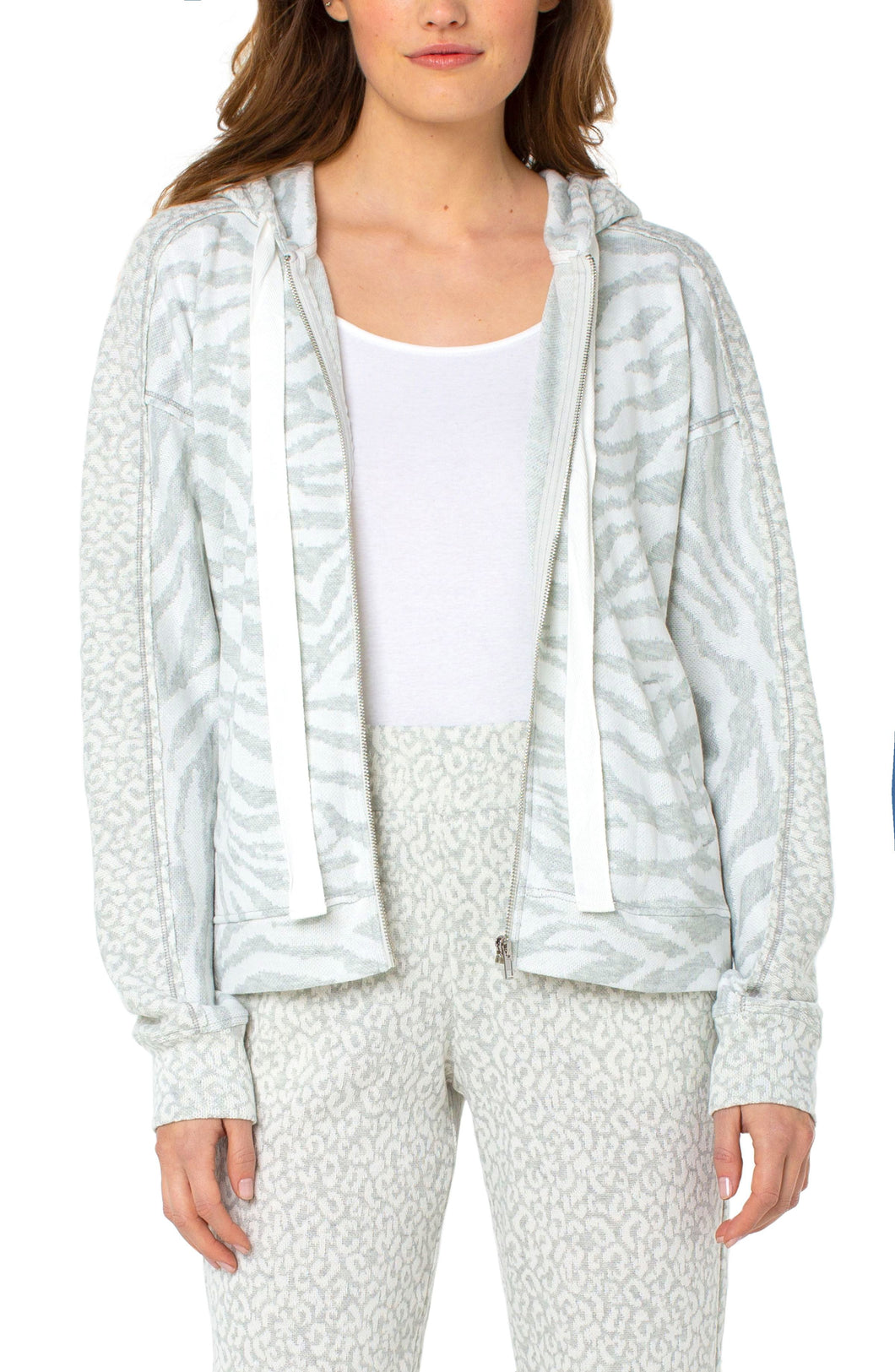 A soft and comfortable fabric, along with a stylish pattern, makes our Zora jacket a must have for the cooler months.  Layer over a white or gray top and pair with your favorite jean or if you are looking for a complete fashionable set, pair with our WINDAM PULL ON WIDE LEG PANT WITH DRAWSTRING IN ZEBRA JACQUARD. Color- White and gray. Jacquard fabrication. Set in hooded neckline with drawstring. Long drop shoulder sleeves.